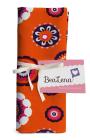 Oranges Stofftuch mit bunten, floralen Mustern. Verpackt mit einem weißen Band und einem Etikett.
