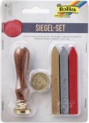 Siegelset mit einem Holzstempel und goldener Siegelplatte. Drei Wachsstifte in rot, gold und silber. Verpackung zeigt die Marke Folia.