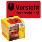Rote Warnetiketten mit dem Text 'Vorsicht zerbrechlich!'. Verpackung zeigt eine gelbe Box mit Etiketten für den Paketversand.
