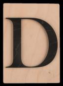 Holzplatte mit dem großen Buchstaben D in schwarzer Farbe. Der Hintergrund ist hell und schlicht.