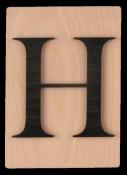 Holzplatte mit dem großen Buchstaben H in schwarzer Farbe. Der Hintergrund ist hell und glatt.