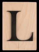 Holzplatte mit schwarzem, großem Buchstaben 'L'. Der Hintergrund ist hell und schlicht.
