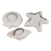 Drei weiße Formen in Muschel- und Sternchen-Design. Sie sind aus einem glatten Material.