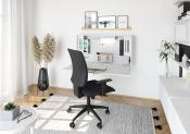 Moderne Büroecke mit einem weißen Schreibtisch. Schwarzer Bürostuhl mit Armlehnen. Wandregal mit Bilderrahmen. Pflanze in schwarzem Topf. Heller Teppich auf Holzboden.