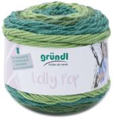 Wollknäuel in Grüntönen. Verpackung mit der Aufschrift 'Lolly Pop' und Anleitung für ein Dreieckstuch.