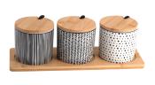 Drei Aufbewahrungsgläser mit Holzdeckeln. Schwarz-weiße Muster und ein Holztablett.