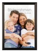 Familienfoto mit vier Personen, die zusammen auf einem Sofa sitzen. Zwei Kinder und zwei Erwachsene lächeln in die Kamera.