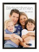 Familienfoto mit vier Personen auf einem Sofa. Zwei Kinder und zwei Erwachsene lächeln in die Kamera.