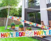 Garten mit Holzterrasse und Pflanzenkästen. Bunte 'Happy Bday'-Girlande hängt über dem Bereich.