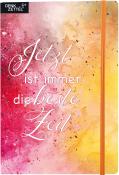 Notizbuch mit buntem Aquarell-Hintergrund. Auf dem Cover steht der Text: 'Jetzt ist immer die beste Zeit'.