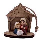 Holzfigur einer Krippe. Zwei Figuren: ein Mann und ein Kind in einer Wiege. Der Mann hält einen Stock. Die Figuren tragen Hüte. Hintergrund aus Holz mit Dach.