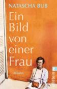 Buchcover mit dem Titel 'Ein Bild von einer Frau'. Eine Frau sitzt vor einer orangefarbenen Wand und hält einen kleinen Rahmen.
