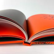 Ein offenes Buch mit orangefarbenen Seiten. Die linke Seite ist schwarz und die rechte Seite hat einen orangefarbenen Hintergrund.