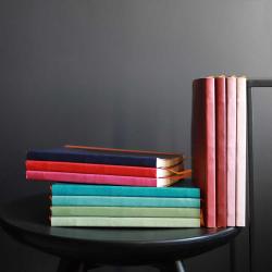 Stapel von Notizbüchern in verschiedenen Farben. Auf einem schwarzen Tisch platziert.