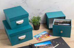 Tealfarbige Aufbewahrungsbox mit goldfarbenem Knopf. Rechteckige Form, schlichtes Design.