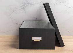 Drei schwarze Aufbewahrungsboxen in verschiedenen Größen. Jede Box hat einen goldenen Griff und ein beschriftbares Etikett.