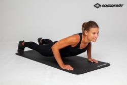 Schwarze Yoga-Matte mit geriffelter Oberfläche. Sie ist aufgerollt und hat ein Logo in der Ecke.