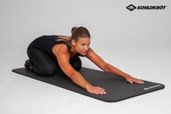 Schwarze Yoga-Matte mit geriffelter Oberfläche. Sie ist aufgerollt und hat ein Logo in der Ecke.