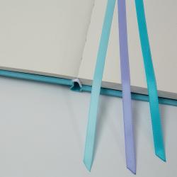 Ein offenes Notizbuch mit gepunkteten Seiten. Drei farbige Lesezeichen in Blau und Lila.