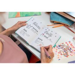 Offenes Notizbuch mit handschriftlichen Notizen zu einem Prinzessinnen- und Party-Thema. Eine Person schreibt mit einem Stift.