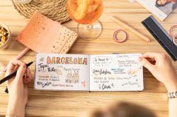 Offenes Notizbuch mit handschriftlichen Notizen zu Barcelona. Getränke und Schreibutensilien auf dem Tisch.
