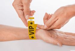 Gelbes VIP-Armband mit schwarzen Sternen und dem Schriftzug VIP. Es hat eine weiße Markierung.