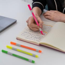 Vier Textmarker in leuchtenden Farben grün, pink, orange und gelb. Dazu gehören passende Kappen in denselben Farben.
