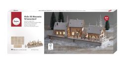 Holzmodell eines winterlichen Dorfes mit drei Häusern und Tannenbäumen. Zwei Rehe stehen auf der Basis.