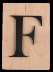 Holzplatte mit schwarzem, großen Buchstaben F. Der Hintergrund ist hell und glatt.