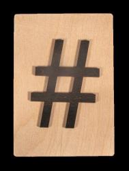 Holzplatte mit schwarzem Hashtag-Symbol. Schlichtes Design auf hellem Hintergrund.