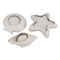 Drei weiße Formen in Muschel- und Sternchen-Design. Sie sind aus einem glatten Material.