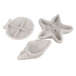 Drei weiße Formen in Muschel- und Sternchen-Design. Sie sind aus einem glatten Material.