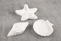 Drei weiße Formen in Muschel- und Sternchen-Design. Sie sind aus einem glatten Material.