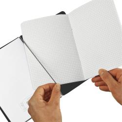 Ein offenes Notizbuch mit kariertem Papier. Eine Hand hält eine Seite auf.