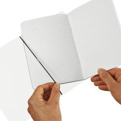 Ein offenes Notizbuch mit karierten Seiten. Eine Hand hält das Buch und zeigt die leeren Seiten.
