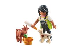 Figur mit dunklen Haaren in Latzhose. Sie füttert ein Zicklein und steht neben einer Ziege.