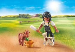 Playmobil Figur mit schwarzem Haar, die zwei Tiere füttert. Im Hintergrund eine grüne Wiese und ein Bauernhaus.
