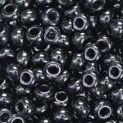 Schwarze, glänzende Perlen aus Glas. Rund, mit einem Loch in der Mitte. Viele Perlen dicht beieinander.