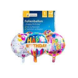 Drei bunte Folienballons mit dem Aufdruck 'Happy Birthday'. Verschiedene Designs und Farben. Verpackung im Hintergrund.