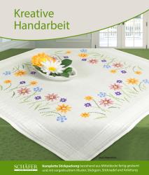 Tischdecke mit buntem Blumenmuster. Eine Schale mit Blumen ist darauf platziert.