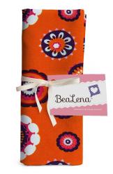 Oranges Stofftuch mit bunten, floralen Mustern. Verpackt mit einem weißen Band und einem Etikett.