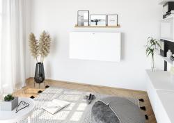 Moderne Büroecke mit einem weißen Schreibtisch. Schwarzer Bürostuhl mit Armlehnen. Wandregal mit Bilderrahmen. Pflanze in schwarzem Topf. Heller Teppich auf Holzboden.