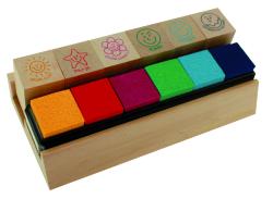 Holzblock mit sechs bunten Schwämmchen. Farben: orange, rot, lila, grün, blau. Oben fünf Stempel mit Smiley-Gesichtern und positiven Worten.