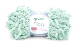 Grüner Wollknäuel mit flauschiger Struktur. Verpackung zeigt ein Beispiel für ein gestricktes Möbelstück.