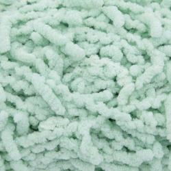Grüner Wollknäuel mit flauschiger Struktur. Verpackung zeigt ein Beispiel für ein gestricktes Möbelstück.