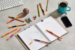 orangefarbener Fineliner mit feiner Spitze. Kappe abgenommen, der Stift liegt auf einer weißen Fläche.