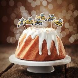Verpackung mit Cake-Toppern in Form von gelben Baggern. Eine Frau lächelt auf der Verpackung.