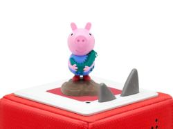 Figur von Peppa Wutz in blauer Kleidung. Im Hintergrund ein Buch mit dem Titel 'Die schönsten Geschichten von Schorsch'.