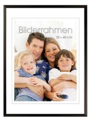Familienfoto mit vier Personen, die zusammen auf einer Couch sitzen. Lächelnde Gesichter, entspannte Atmosphäre.