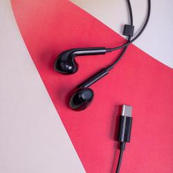 Schwarze Ohrhörer mit einem flachen Kabel. Die Ohrteile sind ergonomisch geformt.